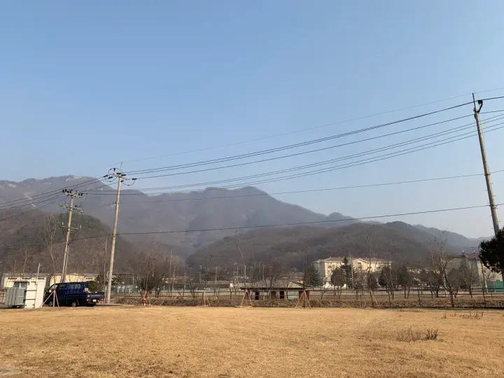 Barrack 숙소 뒤편의 넓은 마당과 산이 보이는 아침 풍경
